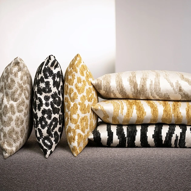 design-kollektion-savannah Gestapelte und aufgestellte Kissen mit Tierfellmustern in Beige, Schwarz und Gold aus der Savannah Kollektion von Rohleder.