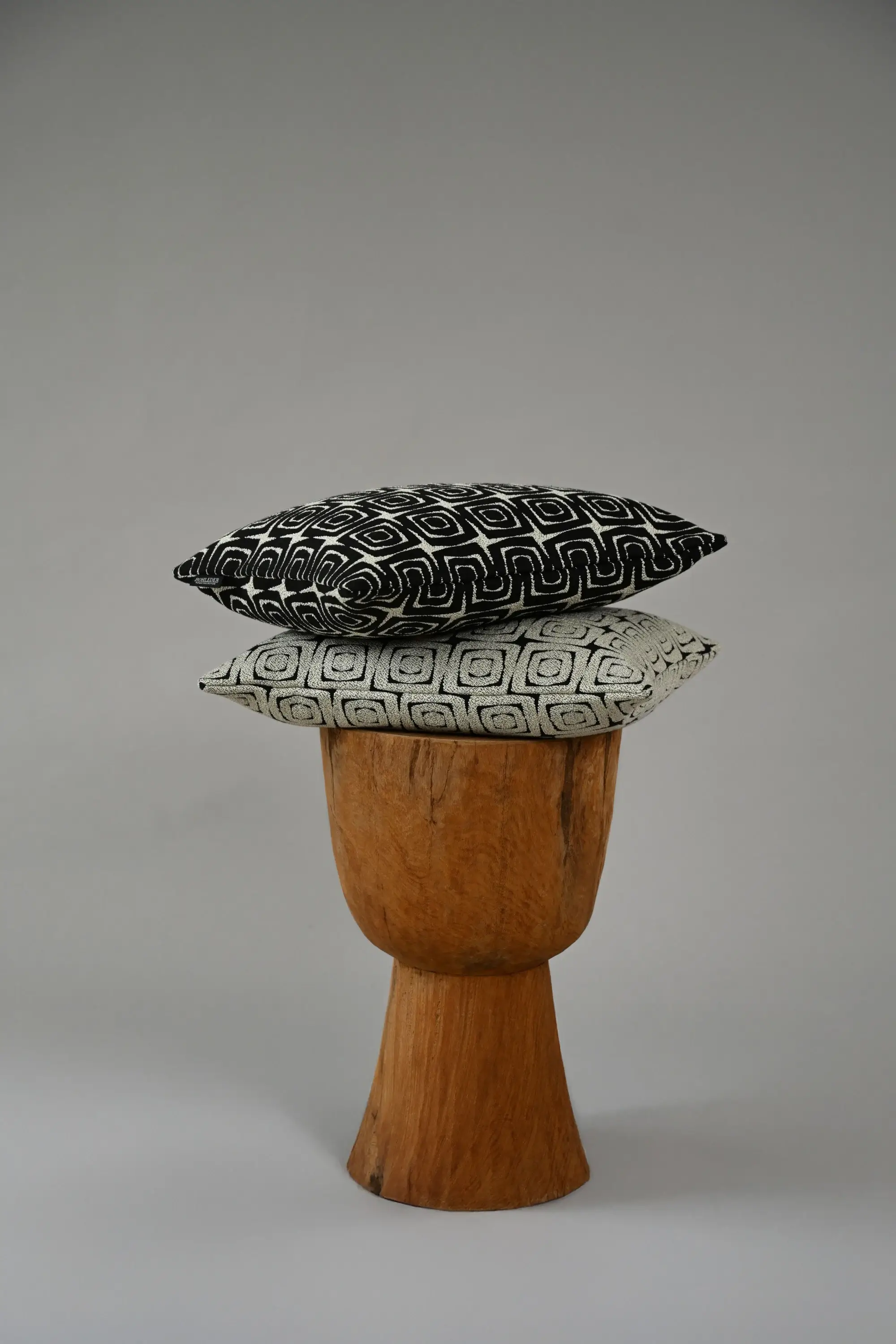 Zwei Turtle-Kissen aus der Tulum-Kollektion von Rohleder auf einem Holzschemel gestapelt.