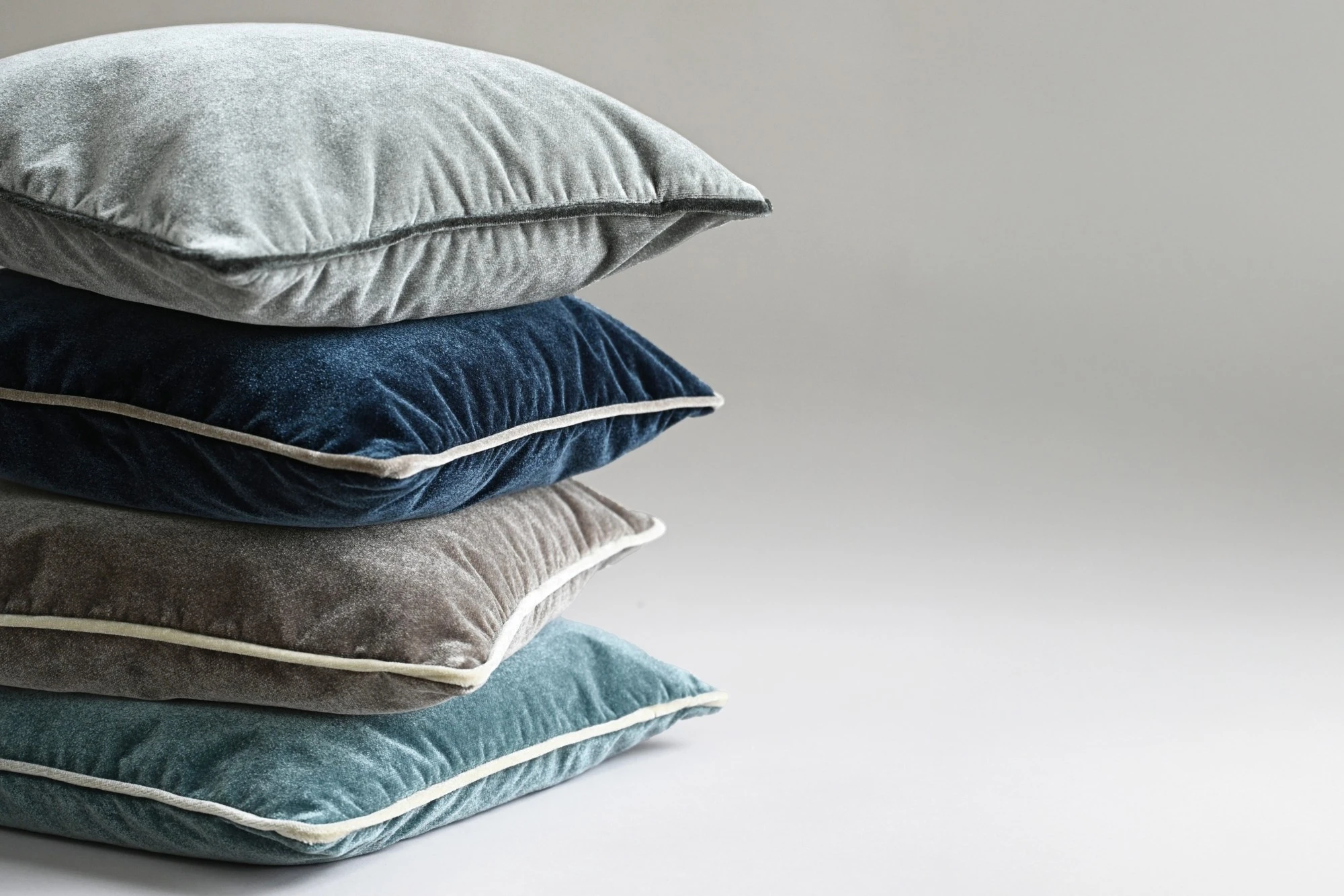 Gestapelte Samtkissen in Blau- und Grautönen aus der Cloud-Kollektion von Rohleder.