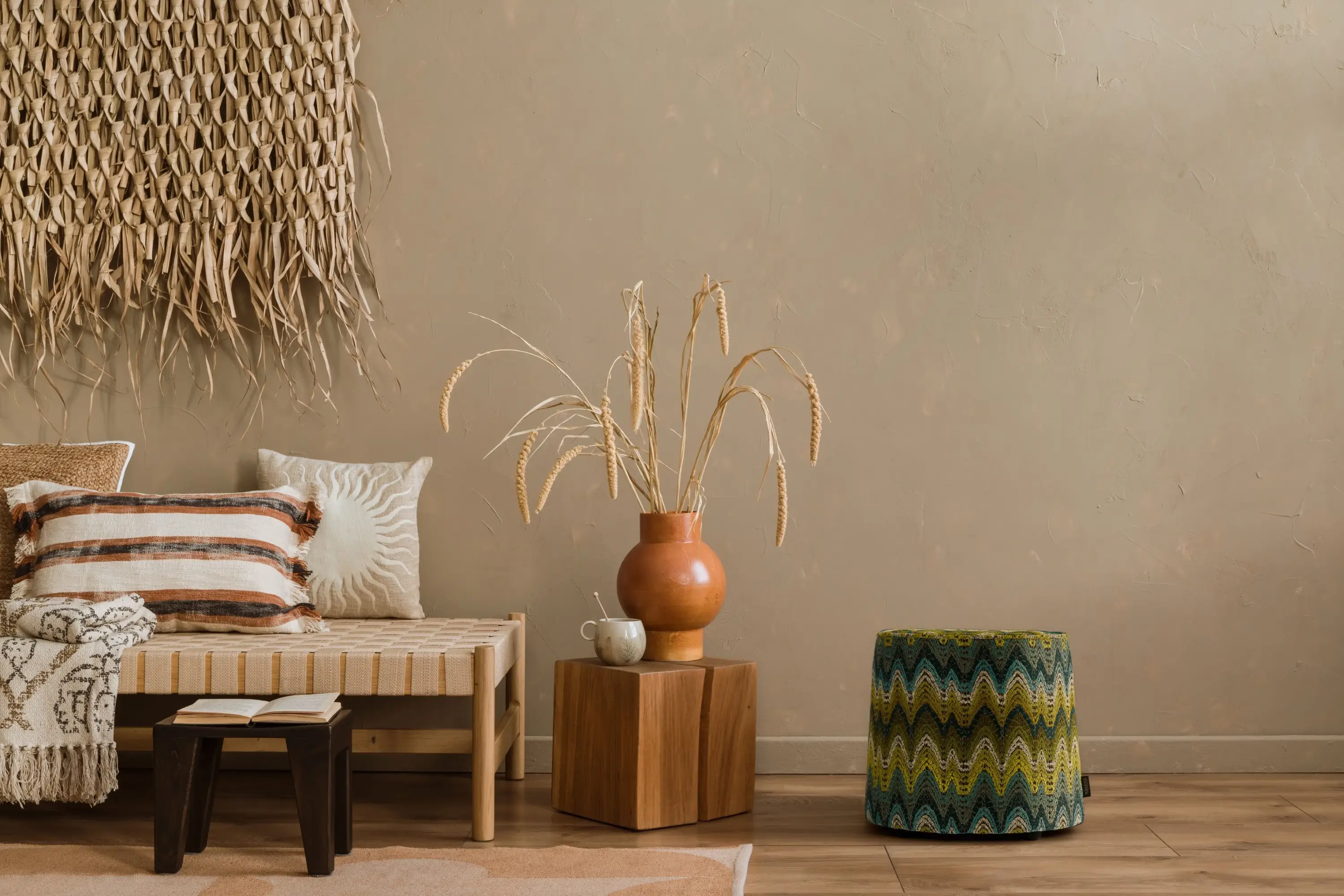 rohleder-pouf-ola-green Wohnszene mit Ola-Pouf aus der Tulum-Kollektion von Rohleder neben Bank mit Kissen.